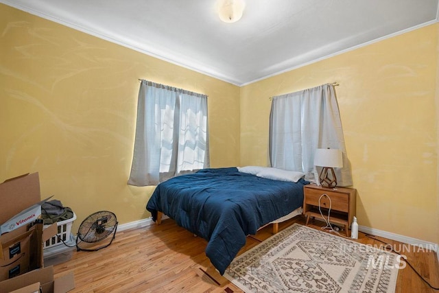 bedroom featuring baseboards, ornamental molding, and wood finished floors
