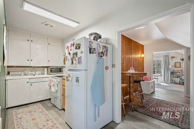 kitchen featuring visible vents, white appliances, white cabinetry, light wood finished floors, and lofted ceiling