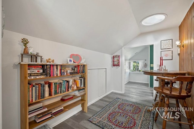 living area featuring wood finished floors, baseboards, and vaulted ceiling