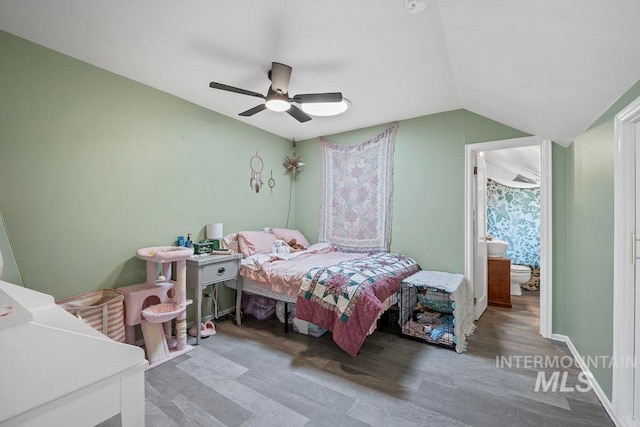 bedroom featuring wood finished floors, ceiling fan, ensuite bath, and lofted ceiling