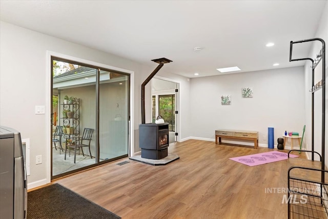 workout area featuring baseboards, a wood stove, light wood-style flooring, and recessed lighting