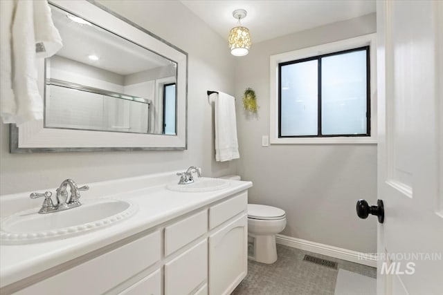 full bathroom featuring visible vents, baseboards, a shower with door, and a sink