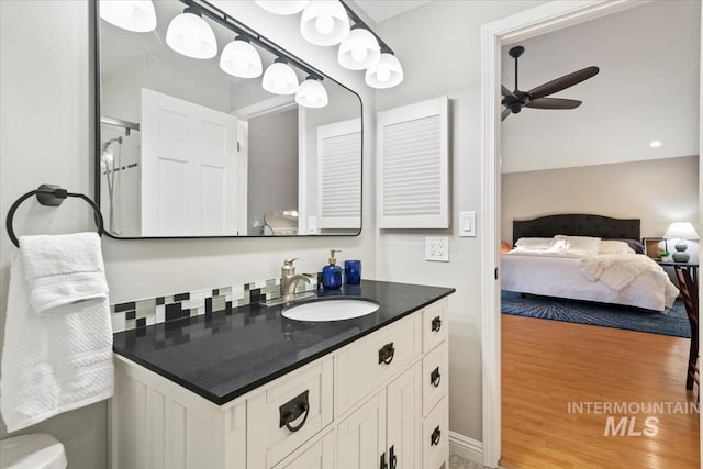 ensuite bathroom with vanity, connected bathroom, toilet, a ceiling fan, and wood finished floors