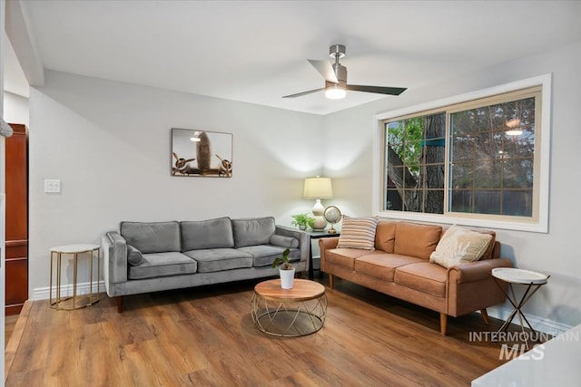 living room featuring wood finished floors, a ceiling fan, and baseboards