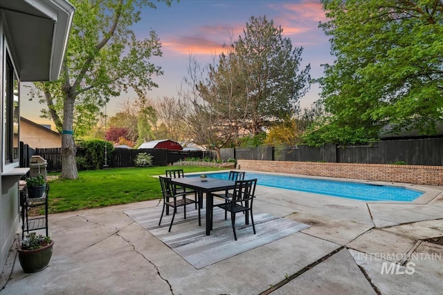 pool at dusk with a fenced in pool, a lawn, a patio, and a fenced backyard