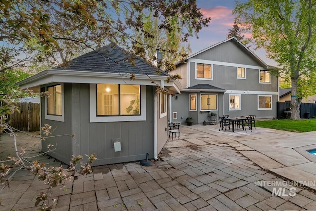 back of property at dusk featuring a patio area and fence