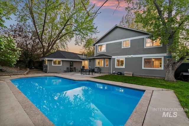 back of property featuring a lawn, an outdoor pool, and a patio area