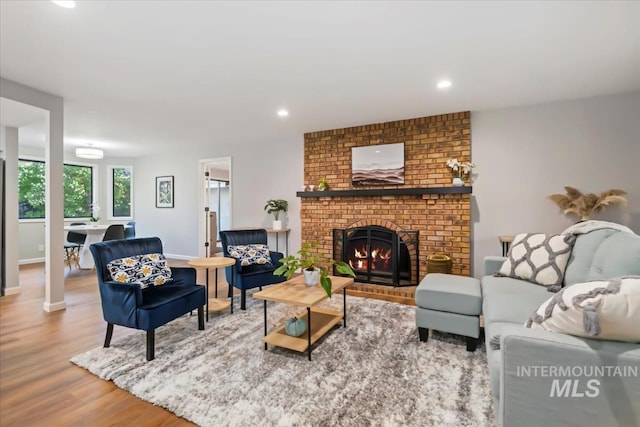 living area with wood finished floors, recessed lighting, baseboards, and a brick fireplace