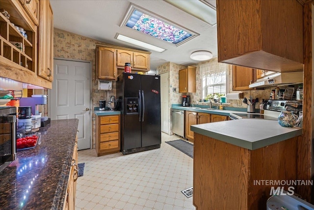 kitchen with custom range hood, stainless steel appliances, sink, and a skylight