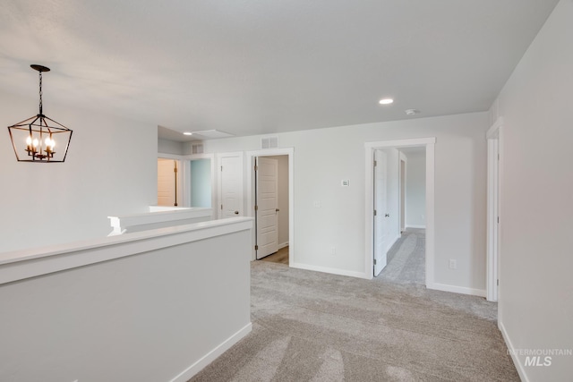 carpeted spare room with an inviting chandelier