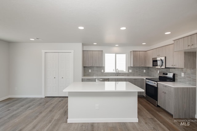 kitchen with a center island, light wood-type flooring, stainless steel appliances, and light brown cabinetry