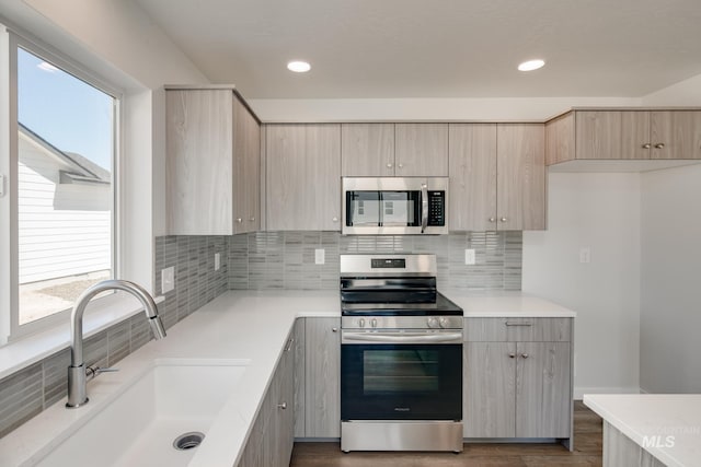 kitchen with sink, light brown cabinets, stainless steel appliances, tasteful backsplash, and dark hardwood / wood-style flooring