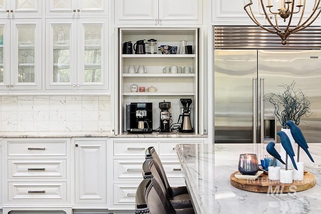 bar with stainless steel built in fridge, an inviting chandelier, and tasteful backsplash