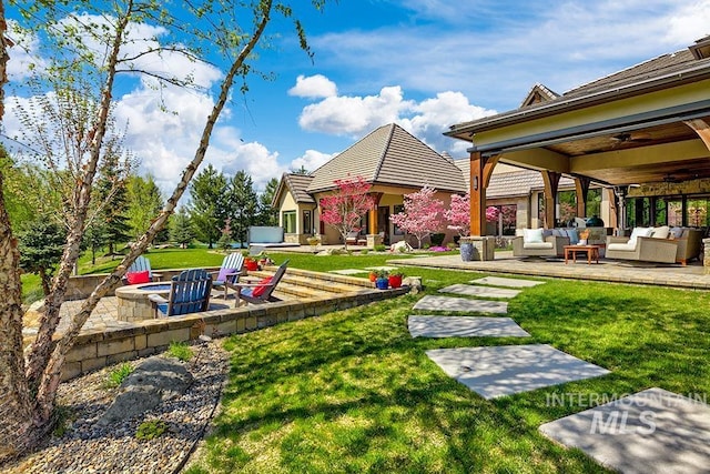 view of yard featuring a patio, a ceiling fan, and an outdoor living space with a fire pit
