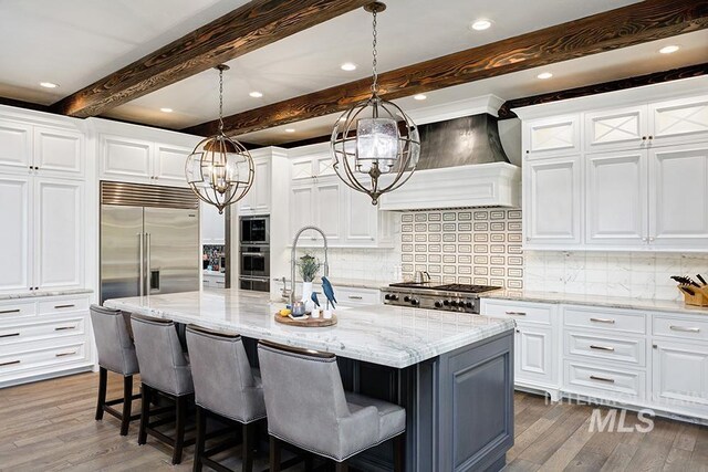 kitchen with white cabinets, wood finished floors, a chandelier, and stainless steel appliances