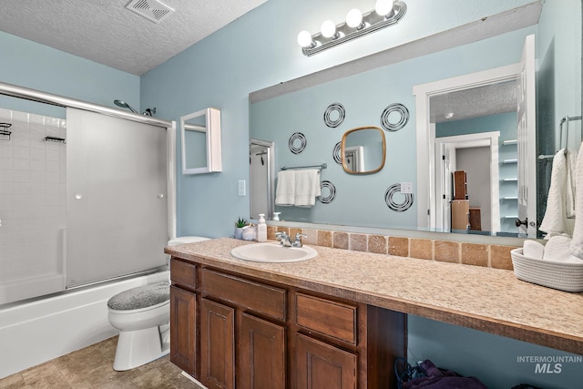 2801 W Lost Rpds, Meridian, ID 83646 - full bathroom with a textured ceiling, vanity, visible vents, toilet, and combined bath / shower with glass door