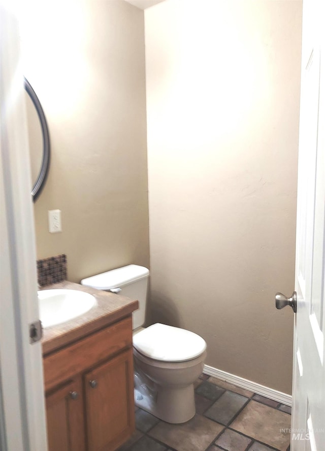 bathroom with baseboards, toilet, and vanity