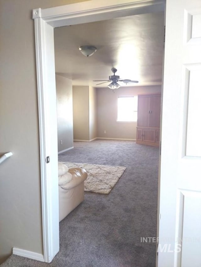 carpeted empty room with a ceiling fan and baseboards
