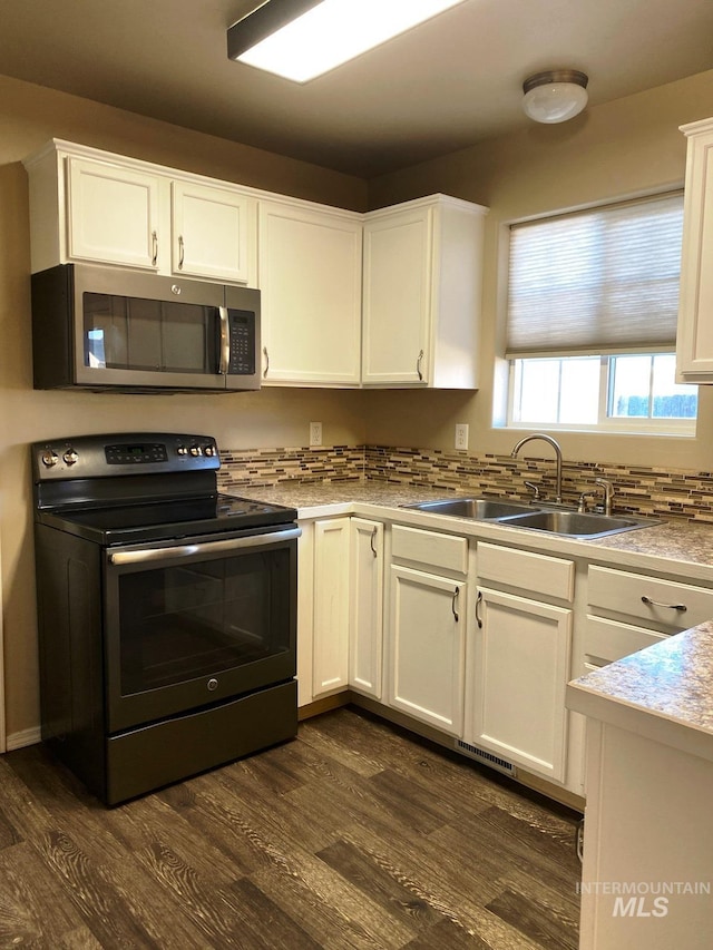 kitchen with stainless steel microwave, electric stove, a sink, white cabinets, and dark wood finished floors