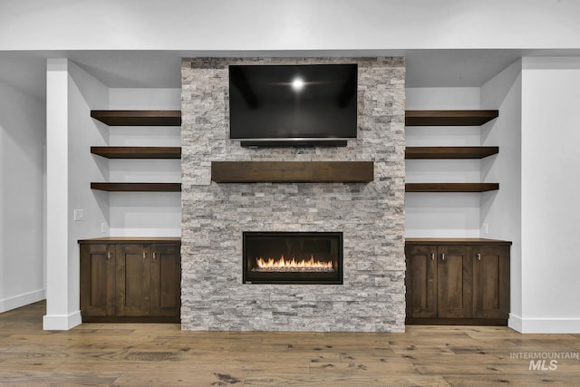 unfurnished living room featuring wood finished floors, baseboards, and a fireplace