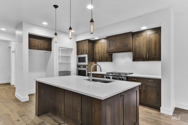 kitchen with appliances with stainless steel finishes, a sink, recessed lighting, baseboards, and tasteful backsplash