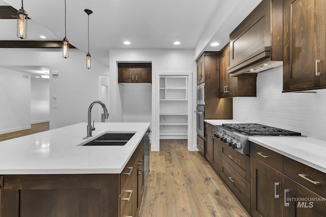 kitchen with a sink, appliances with stainless steel finishes, decorative backsplash, light wood finished floors, and recessed lighting