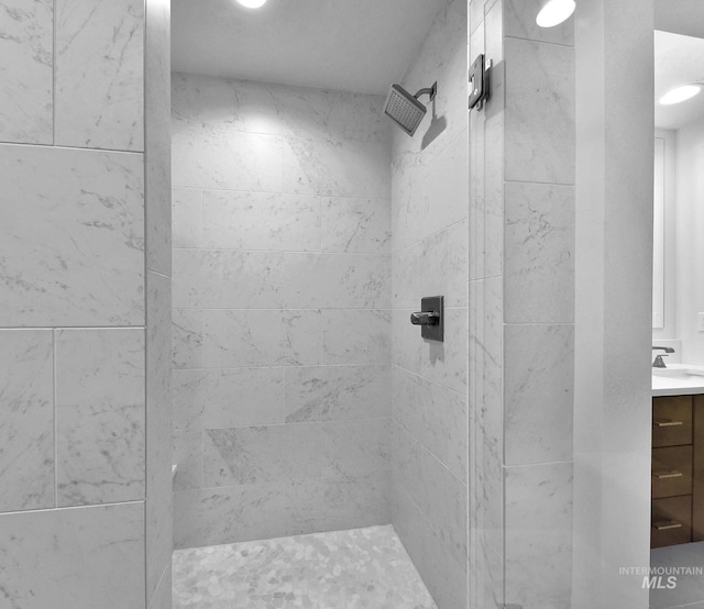 full bath featuring a tile shower and vanity