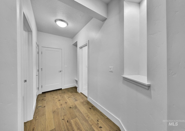 corridor featuring hardwood / wood-style flooring, baseboards, and a textured ceiling