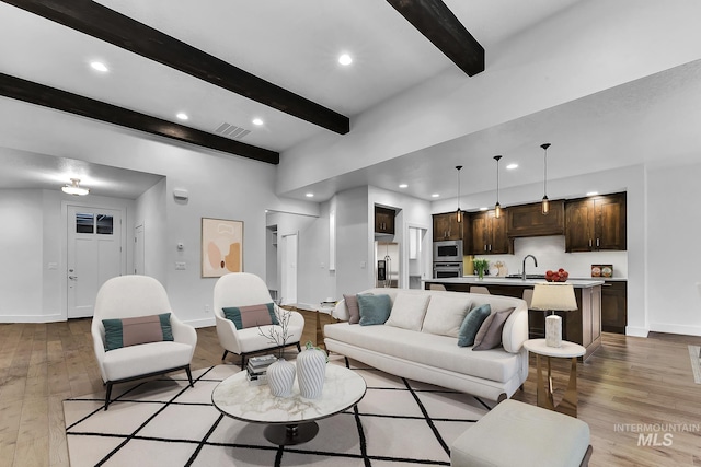 living room with beamed ceiling, light wood-type flooring, baseboards, and recessed lighting