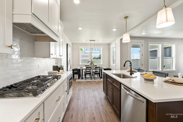 kitchen featuring a sink, white cabinets, light countertops, appliances with stainless steel finishes, and dark brown cabinets