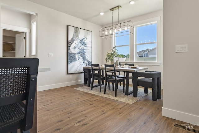 dining room with a notable chandelier, wood finished floors, and baseboards