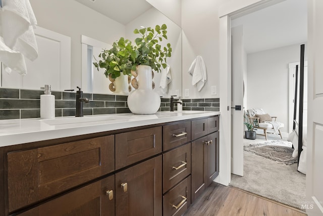 bathroom with double vanity, a sink, decorative backsplash, and wood finished floors