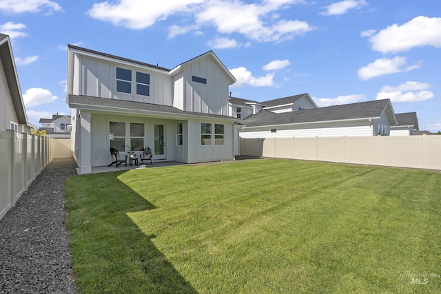 rear view of property with a fenced backyard, a lawn, board and batten siding, and a patio