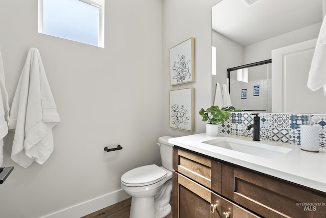 full bath with a stall shower, tasteful backsplash, baseboards, toilet, and vanity