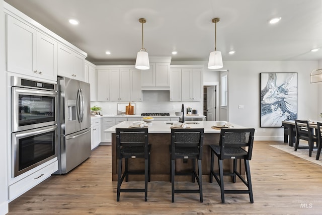 kitchen featuring stainless steel appliances, light wood-type flooring, white cabinets, and light countertops