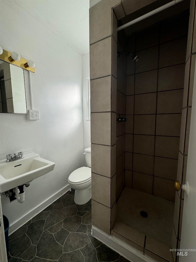 bathroom featuring sink, tile patterned floors, toilet, and tiled shower