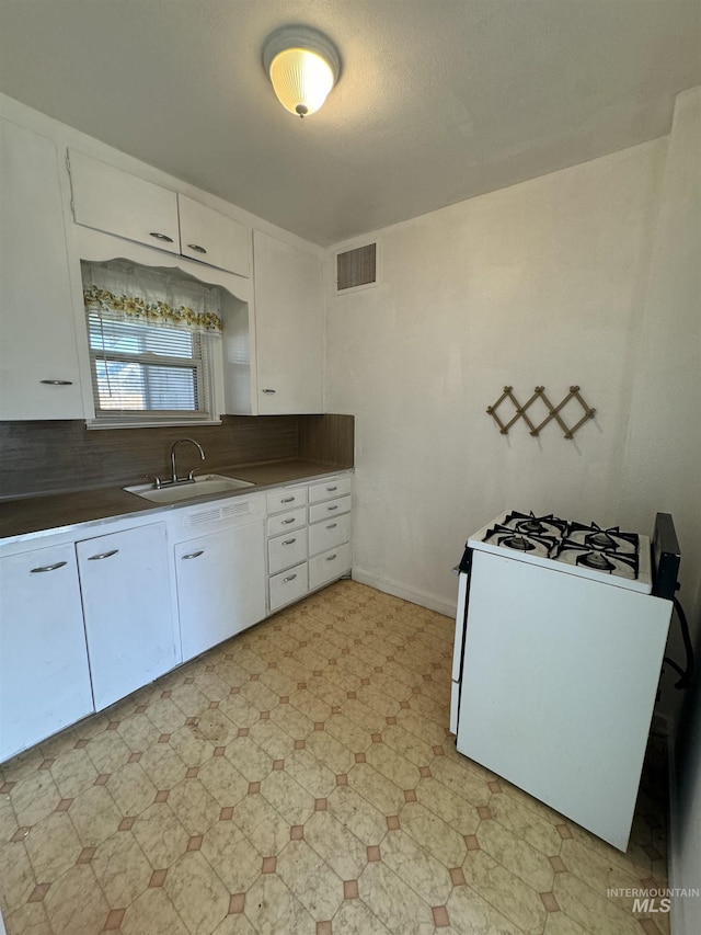 660 SW 2nd St, Ontario, OR 97914 - kitchen with range with gas stovetop, a sink, white cabinets, light floors, and tasteful backsplash