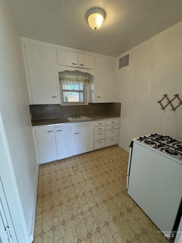 660 SW 2nd St, Ontario, OR 97914 - kitchen with white gas range, a sink, white cabinetry, light floors, and baseboards