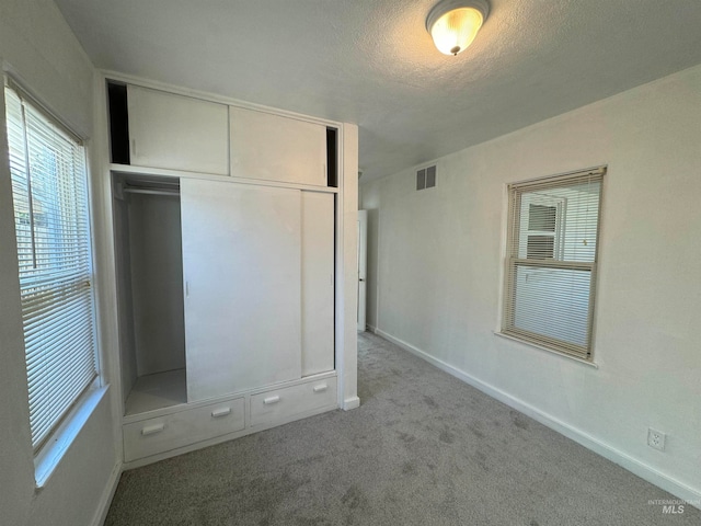 unfurnished bedroom featuring a closet, a textured ceiling, and light carpet