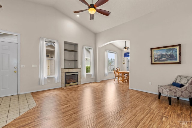 2313 River Oaks Ct, Nampa, ID 83686 - living room featuring a ceiling fan, high vaulted ceiling, light wood-style flooring, a tiled fireplace, and arched walkways