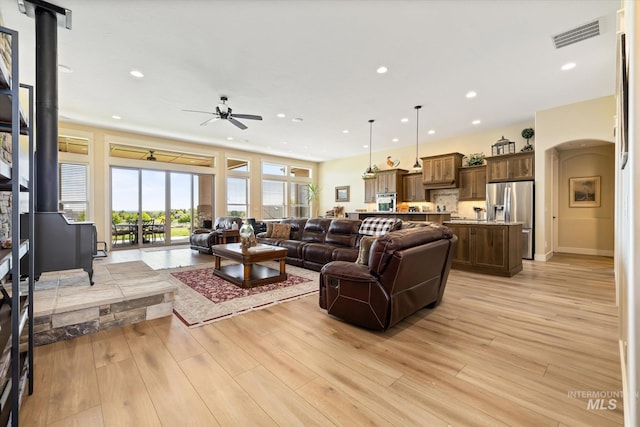 550 W Heikes Ln, Eagle, ID 83616 - living room with ceiling fan, recessed lighting, light wood-type flooring, arched walkways, and a wood stove