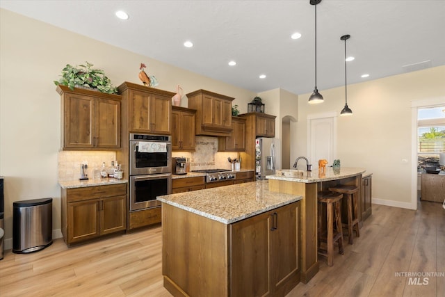 550 W Heikes Ln, Eagle, ID 83616 - kitchen with stainless steel appliances, light wood-style floors, a kitchen island with sink, decorative backsplash, and recessed lighting