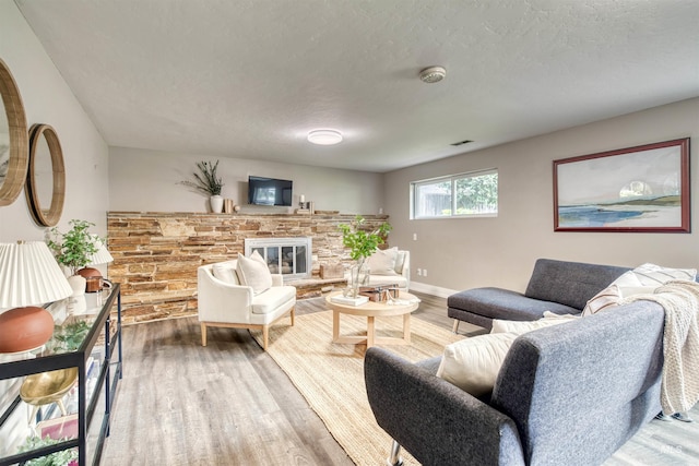 6174 W Winstead Pl, Boise, ID 83704 - living room featuring wood finished floors, a stone fireplace, a textured ceiling, and baseboards