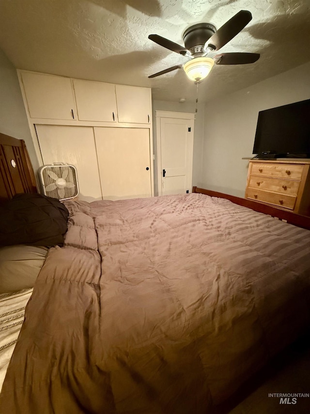 bedroom with ceiling fan, a closet, and a textured ceiling