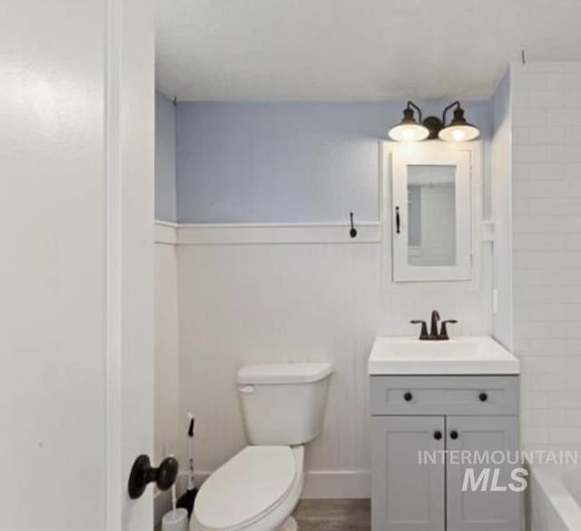 bathroom with hardwood / wood-style floors, vanity, and toilet