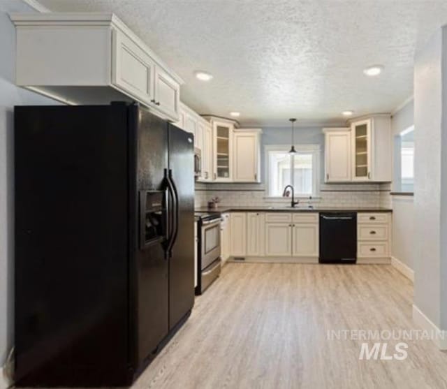 kitchen featuring black appliances, light wood-type flooring, hanging light fixtures, and a wealth of natural light