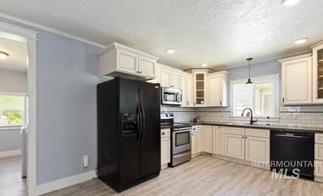 kitchen with decorative backsplash, sink, black appliances, pendant lighting, and light hardwood / wood-style floors