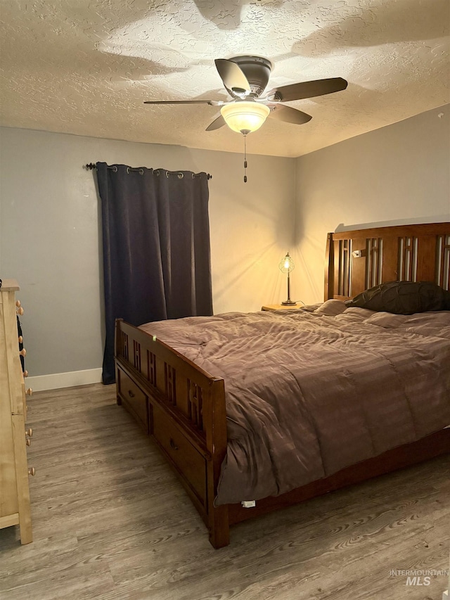 bedroom featuring ceiling fan, wood-type flooring, and a textured ceiling