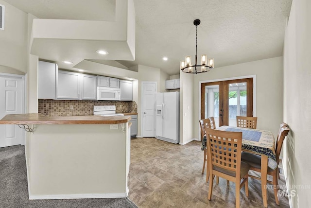 11793 Shelburne, Caldwell, ID 83605 - kitchen featuring white appliances, a chandelier, decorative light fixtures, backsplash, and a peninsula