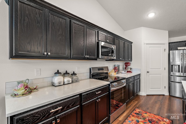 2701 N Ice Fire Pl, Star, ID 83669 - kitchen featuring appliances with stainless steel finishes, dark wood finished floors, light countertops, vaulted ceiling, and dark cabinetry
